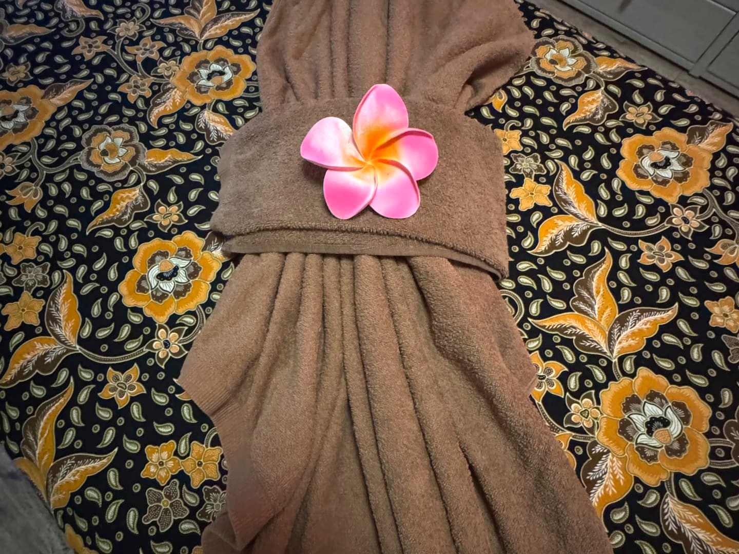 Gefaltetes Handtuch mit Frangipani-Blüte auf balinesischem Batik-Stoff