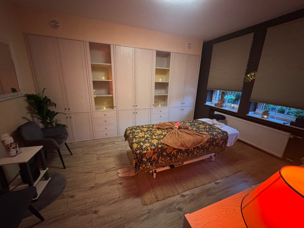 Ruhiger Massageraum mit warmem Licht, Massageliege und Pflanze in Heinsberg
